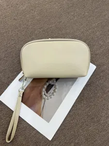 Detail view of the portable leather cosmetic pouch with a wrist strap and smooth zipper closure.