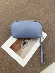 Close-up view of the light blue leather makeup bag zipper and wrist strap details.