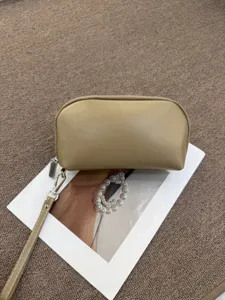 Beige half-arc cosmetic bag with wrist strap, portable travel PU leather pouch for women.