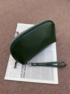 Close-up of the dark green leather clutch bag detail, showing fine texture and zipper.