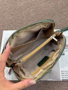 Dark green semi-circular leather clutch bag with multiple compartments for travel and daily use.