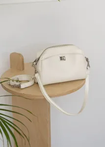 White genuine leather shoulder bag detail showing silver lock closure and strap.