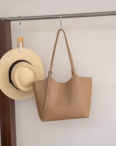 Détail de sac cabas en cuir kaki montrant la bandoulière, la boucle métal et coutures.