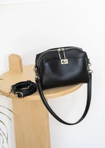 Close-up detail shot of black genuine leather shoulder bag featuring metal lock and zipper.