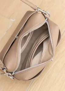 Genuine leather crossbody bag detail showing interior compartments and smooth silver zipper.