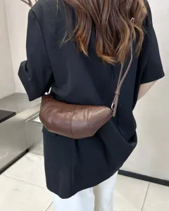 Brown leather croissant cross-body bag, retro minimalist dumpling style for women trend.