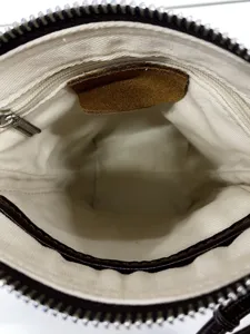 Vista interna della borsa a tracolla minimalista con fodera in tela beige e zip metallica.
