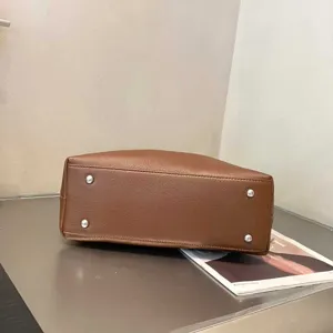Genuine leather handbag detail showing bottom metal feet and premium cowhide texture design.