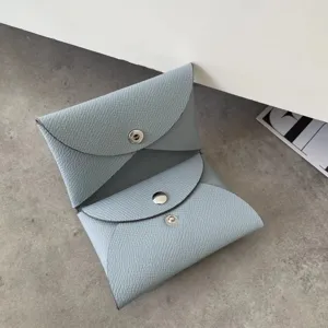 Close-up detail of the light blue leather card holder showing fine grain and metal snap.