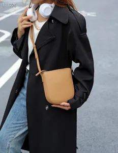 Gros plan sur le sac de téléphone vertical minimaliste en cuir marron, détails de texture.