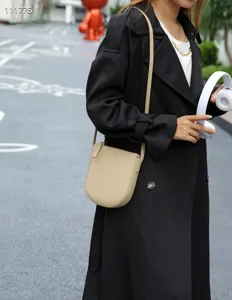 Détail de sac de téléphone portable vertical minimaliste, bandoulière en cuir grainé beige.