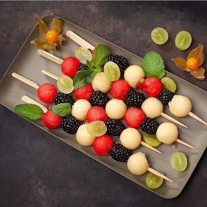 Fresh fruit skewers with watermelon, melon balls and blackberries arranged on a chic plate.