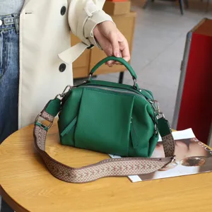Green leather top-handle shoulder bag detail shot, featuring wide patterned strap and metal hardware.
