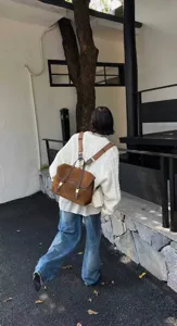 Retro brown suede backpack detail view, casual college style commuter bag with metal buckles.