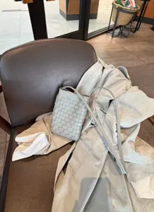 Detail shot of the woven leather mini crossbody phone bag resting on a cafe chair.