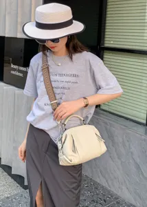 Detailed shot of casual top grain leather handbag with wide shoulder strap in daily wear scene.