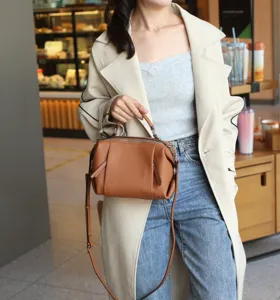 Detailed view of the brown leather crossbody satchel bag showcasing texture and hardware.