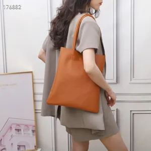 Detailed view of a stylish caramel leather tote bag worn by a model in a clean studio.