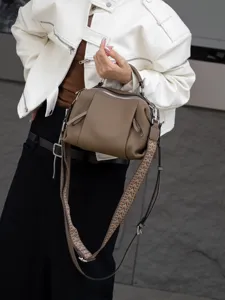 Detailed view of taupe leather handbag with patterned strap, casual crossbody style showcase.