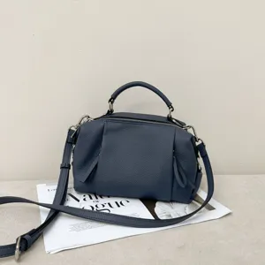Dark blue leather top-handle shoulder bag with geometric panels and detachable strap.