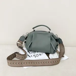 Detail view of genuine leather women handbag, geometric panel design with wide woven strap.