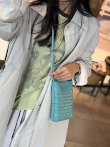 Detailed shot of a trendy woven leather phone crossbody bag worn by model, chic and compact style.