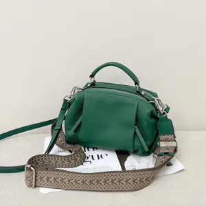 Close-up of green genuine leather handbag showing soft pebbled texture and patterned strap details.