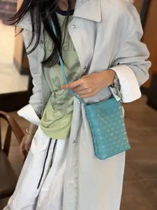 Textured light blue woven leather phone bag detail, stylish crossbody strap and soft sheepskin.