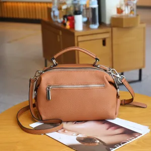 Detailed view of brown leather handbag with zipper pockets, casual shoulder strap and top handle.