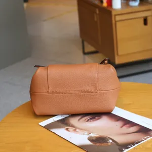 Detailed close-up shot of the brown leather shoulder bag showcasing its unique curved design.