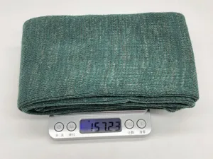 Nahaufnahme des grünen Strick-Waffenschutzes mit feiner Textur und Gewichtsangabe auf Waage.