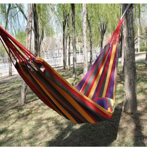Outdoor canvas hammock detail scene, showing colorful striped fabric and natural woods background.