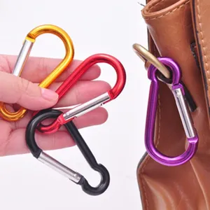 Gros plan détaillé de mousquetons en aluminium coloré illustrant la fixation sur sac.