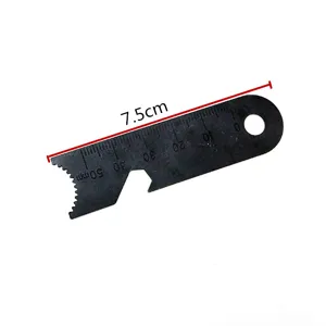 Survival tool detail showing metal scraper ruler scale markings and bottle opener edge.