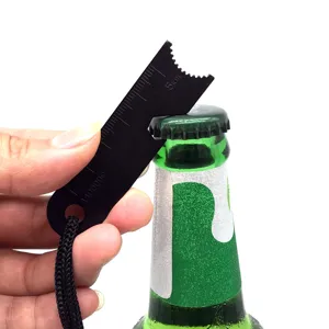 Detail view of black metal survival card bottle opener showing scale marks and bottle opening action.
