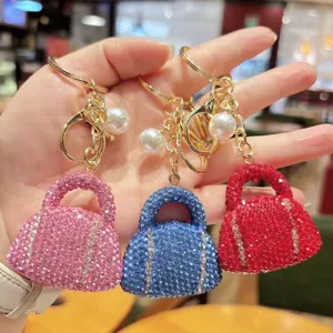 Close-up detail of rhinestone mini handbag keychain pendant with sparkling crystals and pearl.