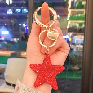Dettaglio portachiavi stella in strass rosso con pentagramma brillante e anello dorato.
