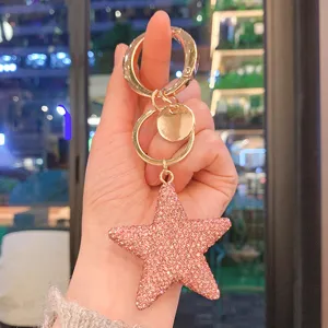 Primo piano dettagliato di un portachiavi a stella in strass rosa con anello dorato.