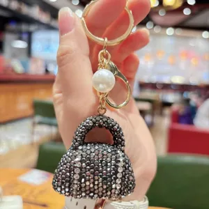 Sparkling rhinestone handbag keychain with gold hardware and pearl bead for keys and bags.