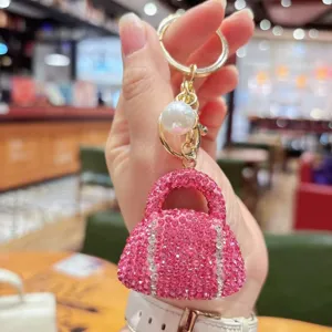 Close-up detail of the sparkling pink rhinestone handbag keychain with pearl charm and gold hardware.