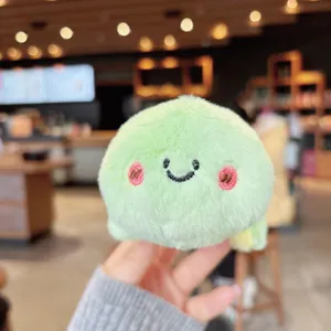 Detailed view of the cute green plush keychain, soft fabric and sweet embroidered smile for bags.