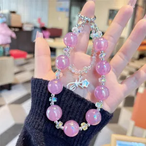 Close-up detail of purple crystal phone charm bead strap with cute bow pendant and shiny finish.