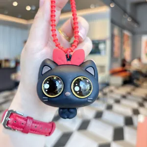Primo piano dettaglio del portachiavi gatto nero carino con fiocco rosso, giocattolo silicone.
