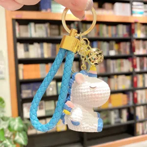 Detailed shot of cute resin unicorn keychain with blue braided strap and golden bell pendant.