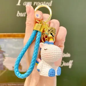 Cute resin unicorn keychain bag charm with blue braided strap and golden bell pendant.