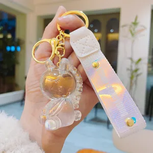 Clear resin unicorn keychain detail view, holographic strap with gold hardware charm.