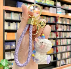 Closeup view of the cute resin unicorn keychain featuring a stylish purple braided strap and bell.