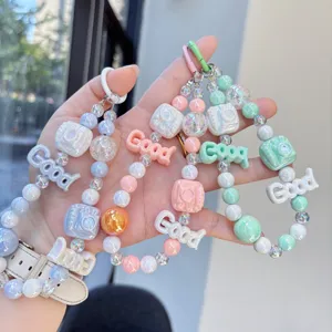Detailed view of cute macaron beaded phone charm with camera and letter pendants.
