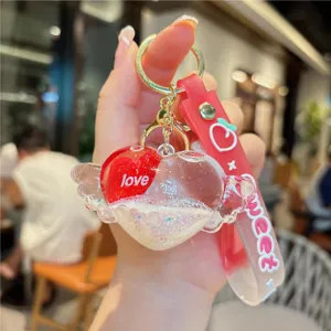 Close-up detail of creative oil-filled quicksand heart keychain with cute wings and strap.