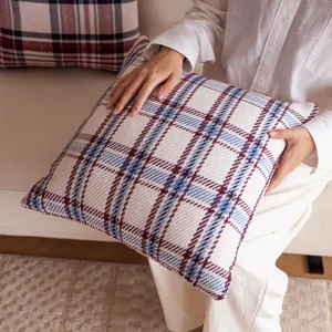 Close-up of soft woven plaid cushion cover fabric texture, showing clear grid pattern details.